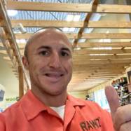 A man in an orange shirt giving the thumbs up